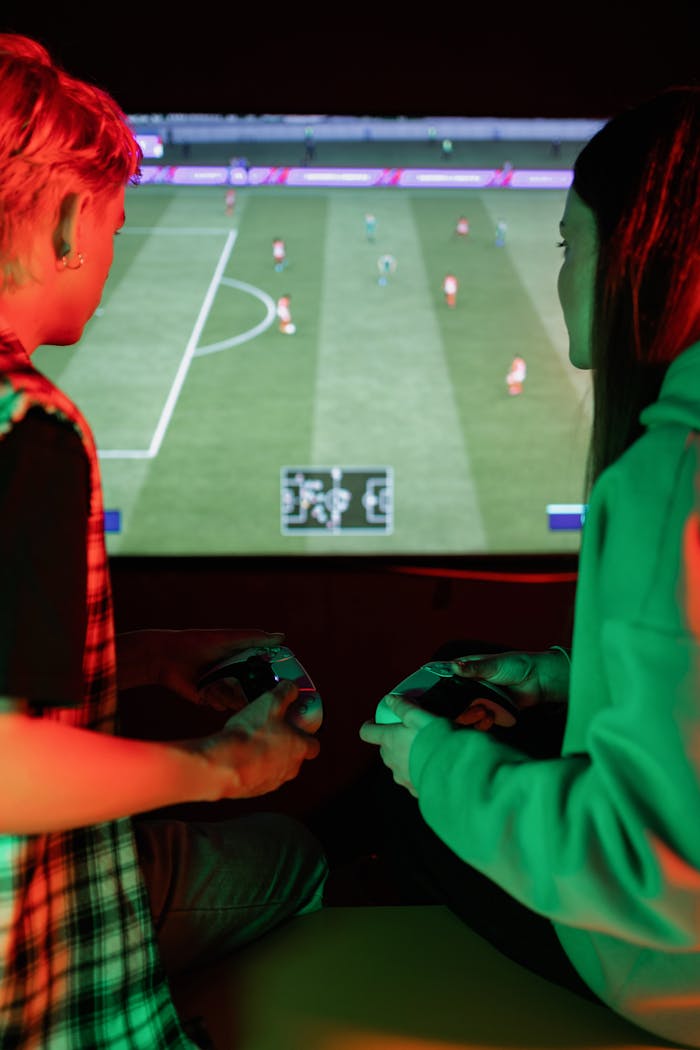 Two teenagers focused on playing a soccer video game at home.